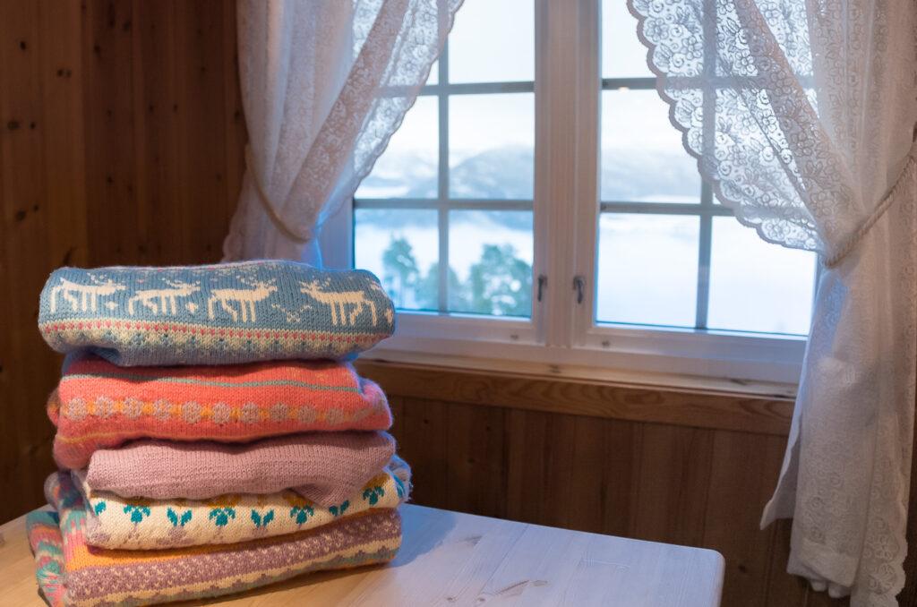 stack of knitted sweaters on a table in a Norwegian cabin