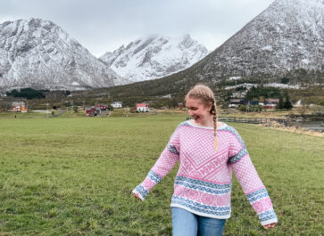woman in pink Norwegian sweater with mountain backdrop in Lofoten, Norway
